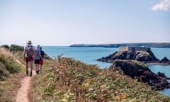 Guardian Pub Walk - The Point, Angle, Wales, UK<br>The Old Point House Inn Walk Pembrokeshire Monday September 05 2022 Pictured: Walkers walking along the path with Thorne Island in the distance Guardian Pub Walk - The Point, Angle, Wales, UK