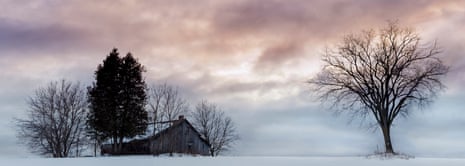 Panoramic view of old barn in winter landscape under overcast sky