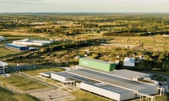 Large industrial buildings and car parks on a green plain