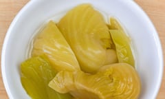 Pickled mustard green in brine, preserved vegetable in salted water in white bowl on wooden background, top view<br>Fermented mustard greens