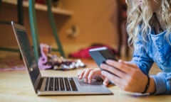 Midsection of female blogger using laptop and smart phone while lying on floor