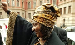 Winnie Mandela with one arm raised in celebration outside the Pretoria high court in 2004.
