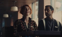 Jessie Buckley and Riz Ahmed sitting side by side, she  smiling, him looking serious