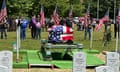 a flag-draped casket is surrounded by headstones and American flags