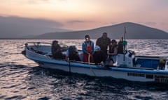 Dr Alex Hearn and his colleagues in a boat in fading light tagging a shark in the Galápagos marine reserve.