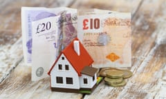 Model house in front of British pound notes and coins