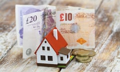 Model house in front of British pound notes and coins