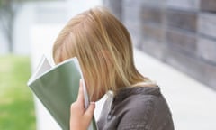 Girl holding a book in front of her face<br>C548WN Girl holding a book in front of her face