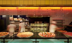 View across counter towards pizza oven with pizza bakers at Voodoo Ray's, Dalston, London.