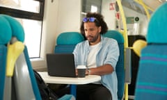 A man uses a laptop on a train