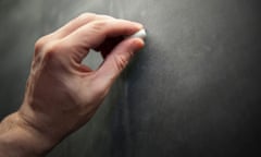 A teacher writes on a blackboard.