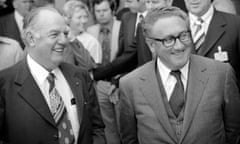 Two jowly white men in suits smile at someone off camera