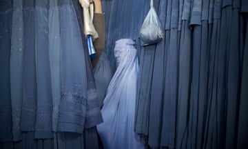 An Afghan woman waits to try on a burqa in a shop in Kabul.