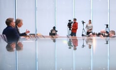 People and cameras at a press conference with reflections