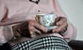 An elderly woman holding a cup of tea