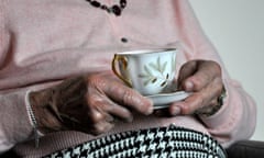 Elderly woman holds cup of tea