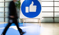 A Facebook employee walks by a sign displaying the "like" icon at the company’s headquarters in Menlo Park, California.