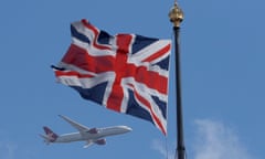 A Virgin Atlantic passenger jet flies past the Union Flag above the Houses of Parliament