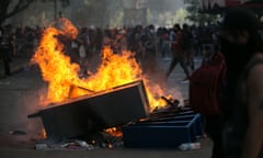 Protesters walk near a burning barricade in Santiago.