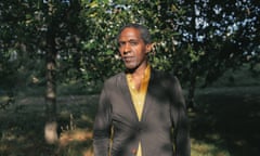Lemn Sissay posing for a photograph in front of trees  in a garden or park