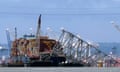 A collapsed bridge sits partially in the water as it rests on a cargo ship