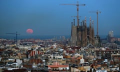 A full moon rises over the Mediterranean sea behind Barcelona.