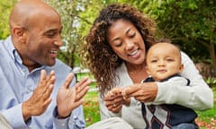 Couple sitting at the park playing with their baby boy