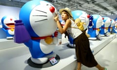 A girl poses for photos with figures of Doraemon during an exhibition of the 45th anniversary of Japanese manga series at a shopping mall in Beijing.