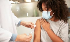 Girl with protective face mask having vaccination at hospital