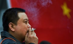 A man smokes in front of a Chinese national flag in Beijing.