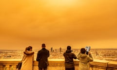 People looking at the panoramic view of Lyon from fourviere in the morning with a yellowish-orange sky over the city of Lyon.