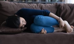 Woman lying on sofa with knees drawn up to chest.