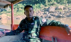 A young man in army fatgues looks at the camera from a boat