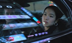 Park Ji-min as Freddie in Return to Seoul, looking out of the window of a car which carries reflections of night-time street signs