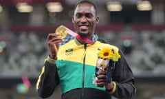 Gold medalist Hansle Parchment poses with the medal he won with the help of a Tokyo 2020 volunteer