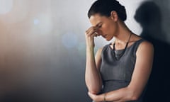 Stressed business woman leaning against a grey wall