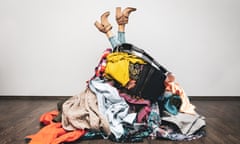 A woman covered in a huge pile of clothes, with just her legs sticking out