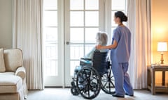 Woman in wheelchair and aged care worker looking out window
