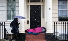 Cold Weather Front From Russian Brings Snow To Across The UK<br>LONDON, ENGLAND - FEBRUARY 26: A woman carrying an umbrella walks past a homeless person sleeping in a doorway during a snow shower on February 26, 2018 in London, United Kingdom. Freezing weather conditions dubbed the "Beast from the East" brings snow and sub-zero temperatures to the UK. (Photo by Jack Taylor/Getty Images)