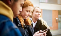 Teenage woman checking her phone with her friends nearby, looking for photos or directions or sending a message<br>GettyImages-948544054