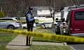 A police officer stands surrounded by police tape.