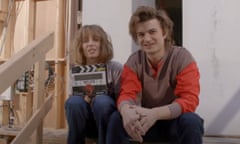 young man and woman sitting on wooden steps holding a film clapperboard