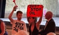 Just Stop Oil protesters holding an air horn and a small banner in front of the stage at Glyndebourne