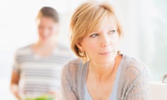 Mother leaning on kitchen counter, out-of-focus daughter in background