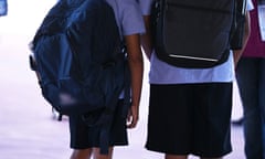 A stock image of two primary school children wearing school bags