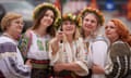 Women wearing traditional blouses in white with rich embroidery, pose for a photo