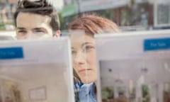 Couple looking at display of advertisements in estate agent