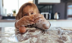 Little girl breaking an egg on kitchen counter covered with flour. Girl child learning cooking in the kitchen at home and making a mess.<br>PGDX6T Little girl breaking an egg on kitchen counter covered with flour. Girl child learning cooking in the kitchen at home and making a mess.