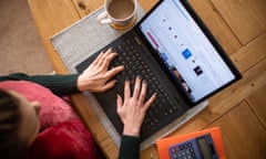 A woman is seen using a laptop on a dining room table set up as a remote office to work from home.