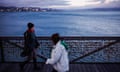 People walk alongside the sea in Wellington, New Zealand